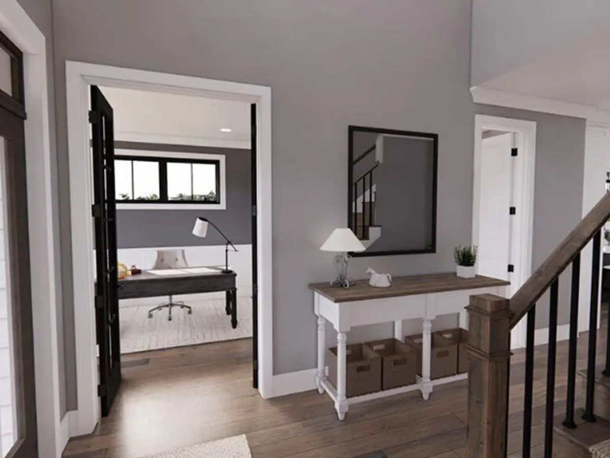 hallway with gray walls, a hardwood brown floor, a stairway, a mirror on the wall, and small cabinets underneath the mirror.